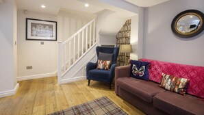 A living room with a staircase, a blue armchair, a red sofa, and a patterned rug. - The Bingham, Fossgate  Apartments Central York (York)