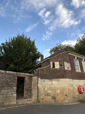 A brick building with a stone wall, a fire hydrant, and a clear sky.