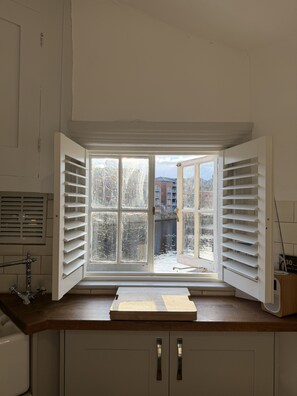 A kitchen with a bay window, a wooden countertop, and cabinets.