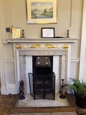 A fireplace with a marble surround, a framed picture above it, and a fire safety sign.
