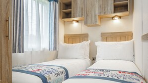 Une chambre avec deux lits, des têtes de lit en bois et des étagères intégrées au-dessus des lits.