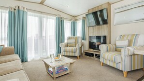 Un salon moderne avec un canapé, des fauteuils, une table basse et un téléviseur à écran plat.