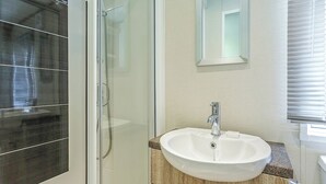 Une salle de bain avec une douche à parois de verre, un lavabo blanc et un miroir au-dessus.