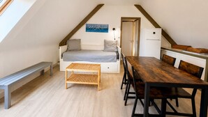 A loft-style room with a bed, a dining table, and a kitchenette.