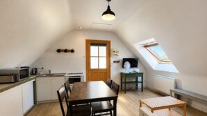 A compact kitchen with a dining table, a TV, and a fan.