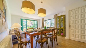 Un comedor con una mesa y sillas de madera, una lámpara y un aparador con puertas de cristal.