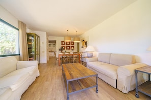 Un salon spacieux avec une table basse en bois, deux canapés et un coin repas comprenant une table et des chaises.