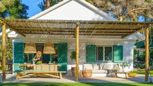 Una casa con piscina, un porche cubierto y una zona de comedor con mobiliario de exterior.