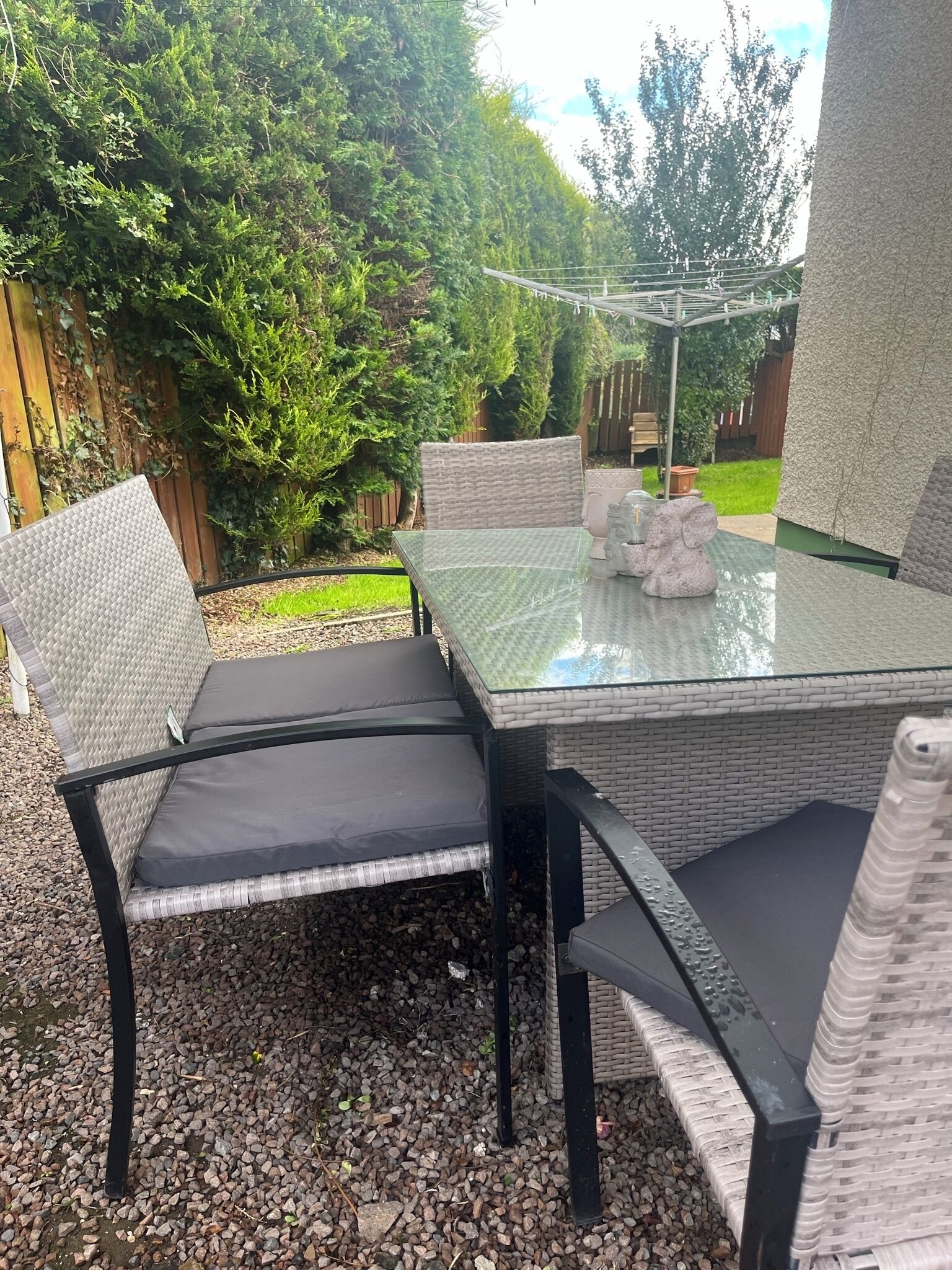 An outdoor patio with a glass-top table and wicker chairs.