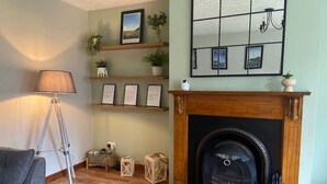A living room with a fireplace, a lamp, a sofa, and shelves with framed pictures and plants.