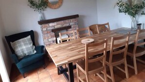 A dining area with a wooden table and chairs, a brick fireplace, and a blue sofa.