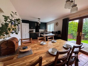 Una cocina moderna con comedor, mobiliario de madera y vistas al jardín.