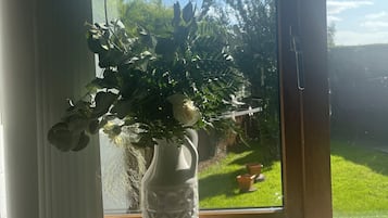 Un vase blanc avec une plante posée sur un rebord de fenêtre.