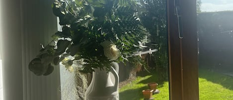 Un jarrón blanco con una planta en un alféizar.