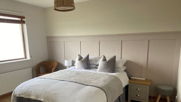A bedroom with a bed, bedside tables, a chair, and a small stool.
