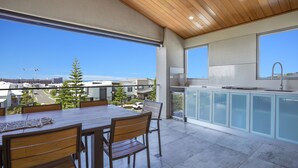 A modern kitchen with a large window, a dining area with a wooden table and chairs, and a view of the cityscape.