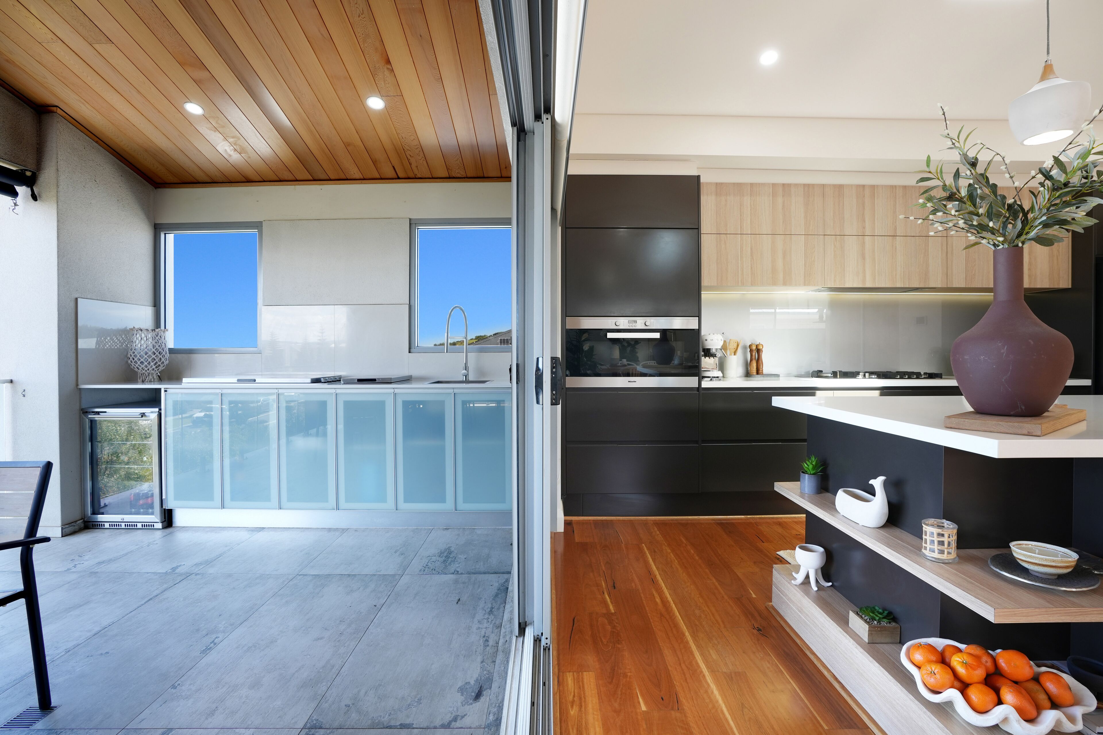 A modern kitchen with a large island, built-in appliances, and a view of the outdoors.