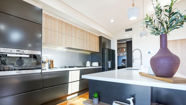 A modern kitchen with stainless steel appliances, wooden cabinets, and a central island with a vase.