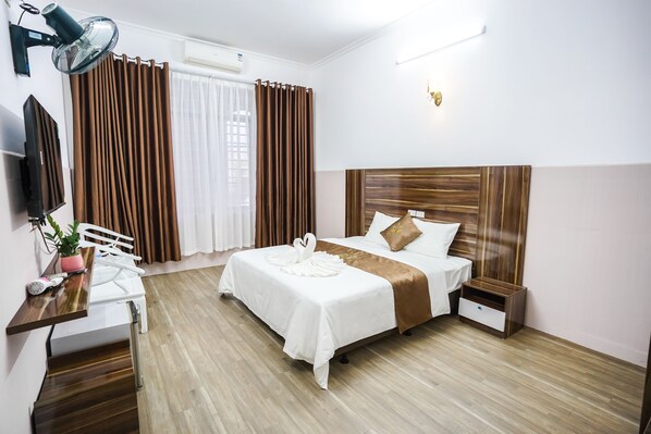 Une chambre d’hôtel comprenant un lit, une table de chevet, une commode, un bureau, une chaise et un téléviseur.