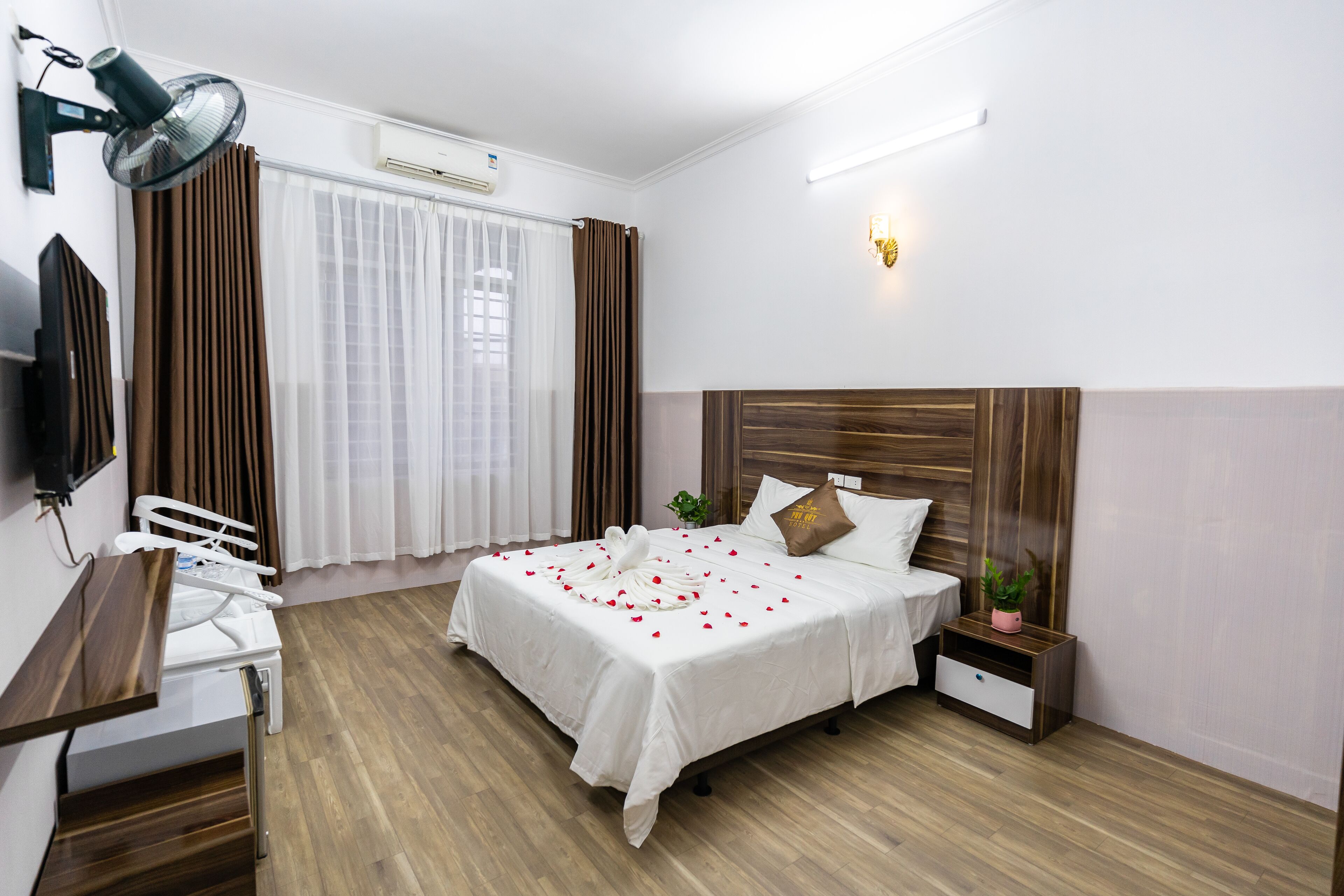 A neatly arranged hotel room with a bed, bedside table, and a desk with a chair.