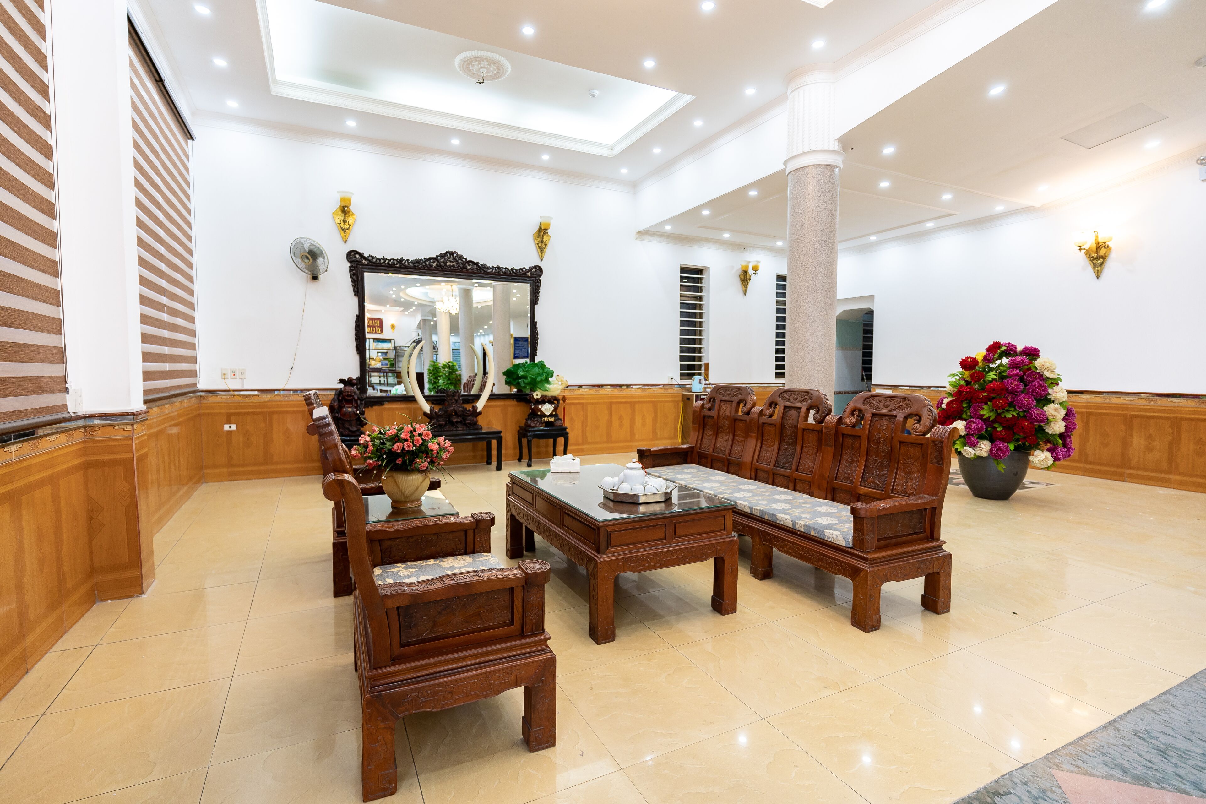 A spacious lobby with wooden furniture, a large mirror, and a potted plant.