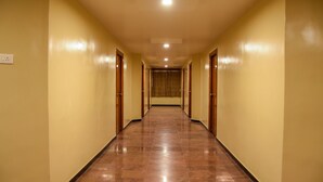 Un pasillo largo y estrecho con suelo pulido y puertas de madera a ambos lados.