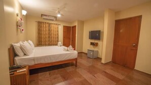 Una habitación de hotel con cama, escritorio, televisor y armario.