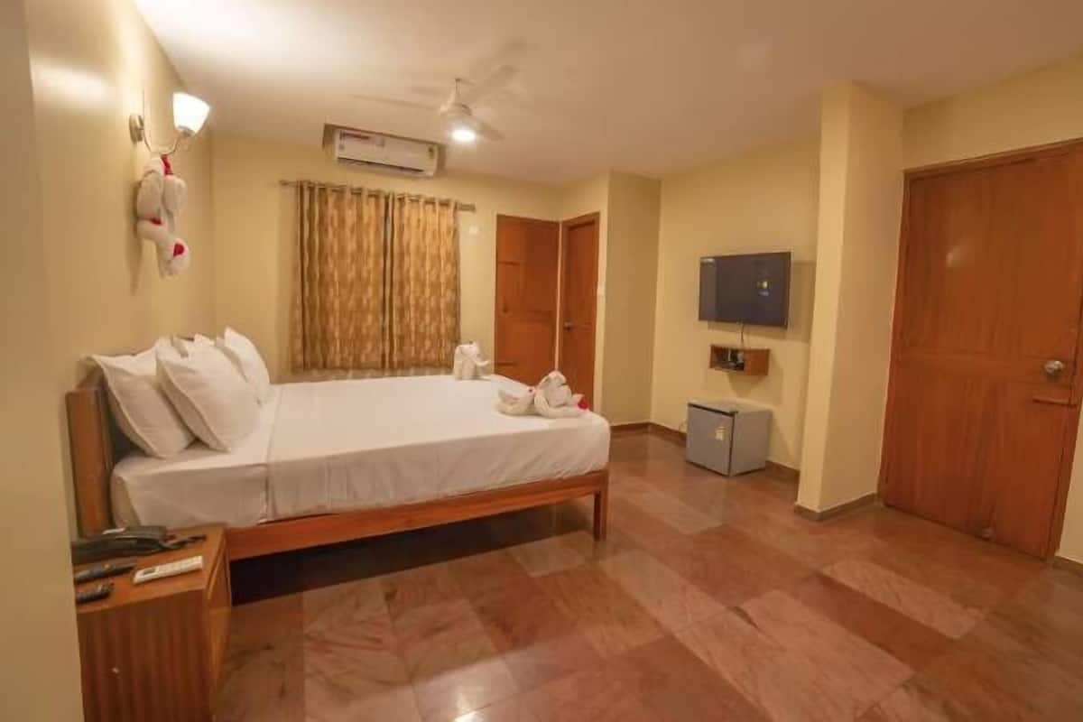 Una habitación de hotel con cama, escritorio, televisor y armario.