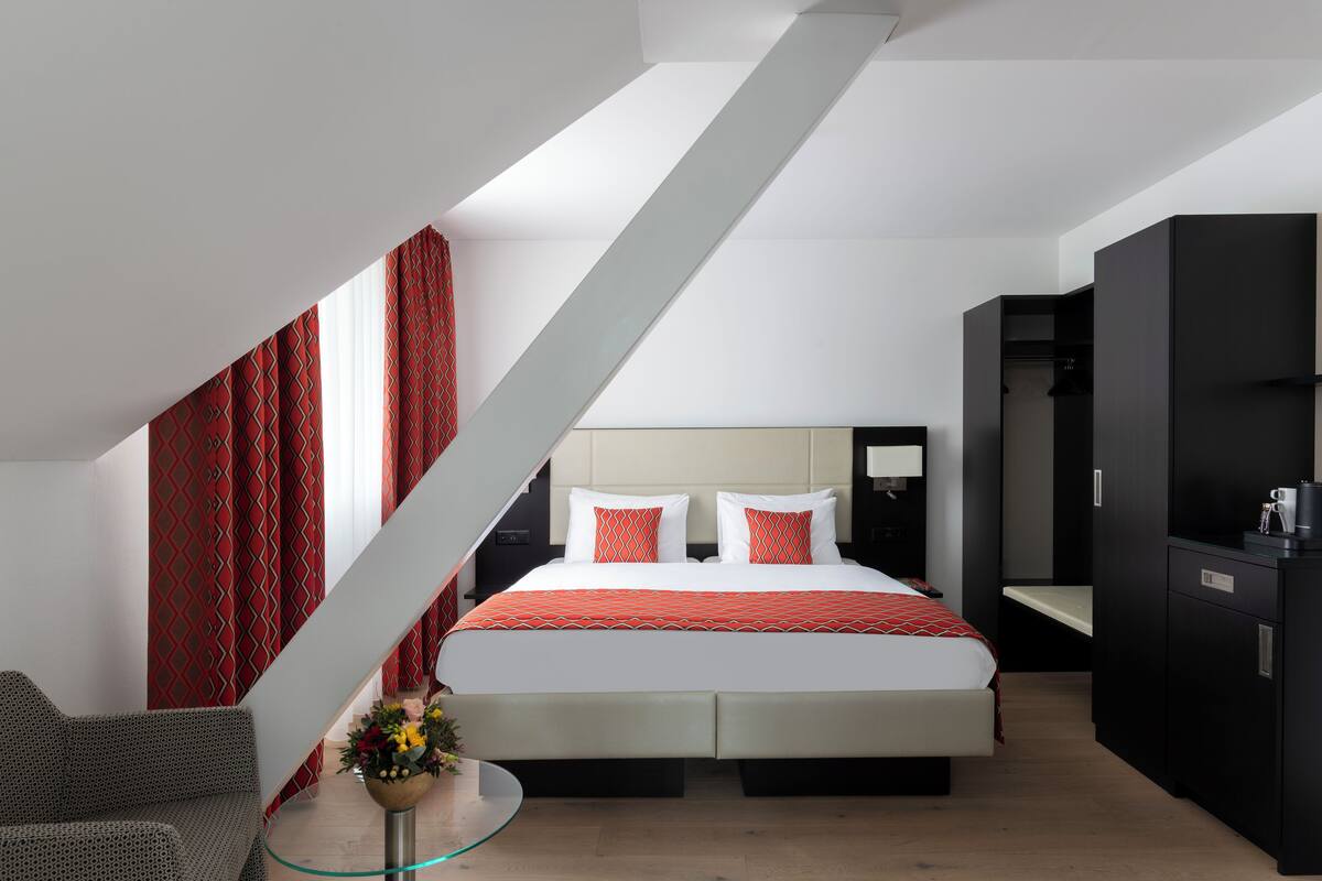 Ein modernes Hotelzimmer mit einem großen Bett, einem Glastisch und einer Treppe.