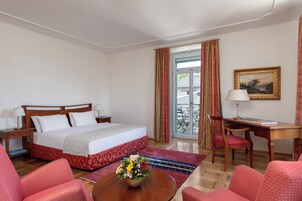 Habitación de hotel con cama, escritorio, silla y vistas al exterior.