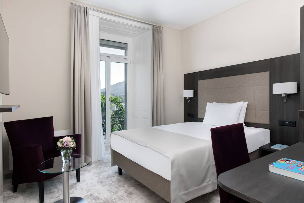 Ein Hotelzimmer mit einem Bett, einem Schreibtisch, einem Stuhl und einem Glastisch.