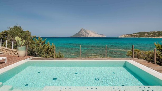 Piscina com vista para o mar e uma montanha.