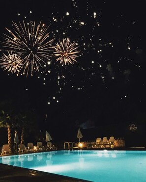 A nighttime pool area with lounge chairs and umbrellas, and fireworks in the sky. - Trulleto Dell'itria - Martina Fr... (Martina franca)
