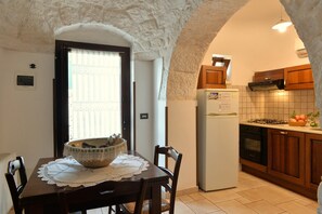 Enjoy meals in this charming dining area with a wooden table and lace tablecloth, surrounded by an arched ceiling.