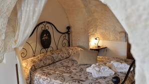 A cozy bedroom with a patterned bedspread, a decorative headboard, and a bedside table with a lamp.