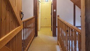 A wooden staircase leading to a door with a light fixture above. - 2 bedroom accommodation in Pontyberem, Carmarthenshire (Pontyberem, Carmarthenshire)