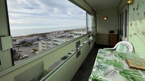 A balcony with a view of a coastal town, a table with a leaf-patterned tablecloth, and a wall with a spider web decoration. - 1-Bedroom Apartment near Beach, Saint-Hilaire-de-Riez (Saint-Hilaire-de-Riez)