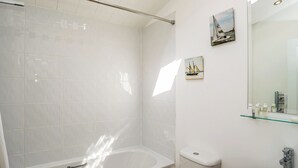 A bathroom with a bathtub, toilet, and sink, with a glass shelf above the sink and a painting on the wall. - Carisbrooke Premier Lodge (Wootton, Nr Cowes)