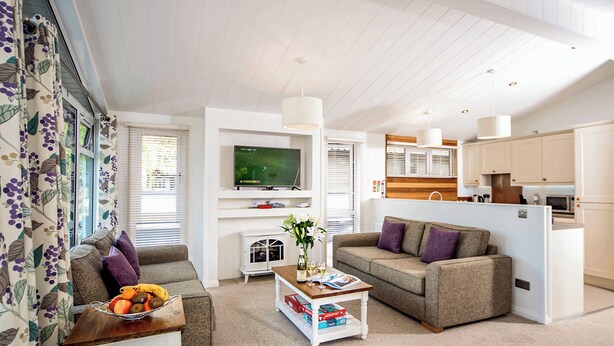 A modern living room with a sofa, coffee table, and TV. - Carisbrooke Premier Lodge (Wootton, Nr Cowes)