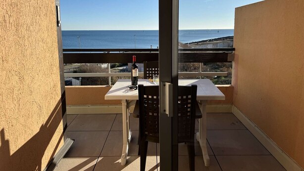 A balcony with a table and chairs, overlooking a coastal view. - Quiet Studio Cabin, Close to Beach, Washing Machine, Pets OK (Cap d'Agde)
