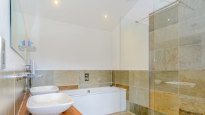Un baño moderno con tocador de madera, dos lavamanos, bañera y cabina de ducha de vidrio.