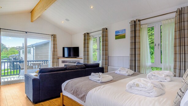 Un dormitorio con cama, sofá, televisión y balcón con vistas.