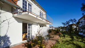 Une maison à deux étages dotée d’un balcon, d’une porte donnant sur un porche abrité et d’un chemin pavé en briques.