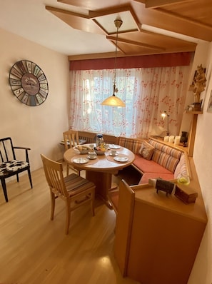 Un coin repas avec une table ronde, des chaises et une fenêtre agrémentée de rideaux à motifs floraux.