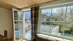 A room with a sofa, a dining table, and a view of a balcony with outdoor furniture. - salzkammergut lake region (ebensee) - 8 pers. - pets welcome - garden - terrace (Ebensee)