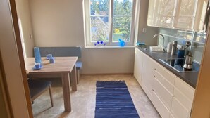 A compact kitchen with a window, a dining area with a table and chairs, and a blue rug. - salzkammergut lake region (ebensee) - 8 pers. - pets welcome - garden - terrace (Ebensee)