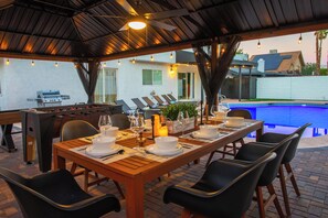 Un espace extérieur aménagé pour les repas, avec une piscine, un barbecue et des chaises longues.