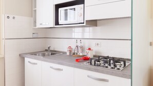 A kitchen with white cabinets, a microwave, a sink, and a gas stove. - A Pass by St. Peter's 121 (Roma)
