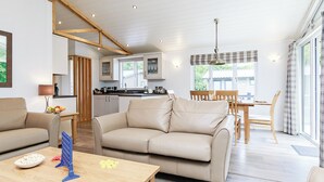 A modern interior with a sofa, dining table, and kitchen area. - Hartfield Watersedge Lodge (Newton Saint Loe, Nr Bath)