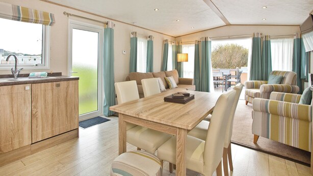 A spacious room with a dining table, chairs, a sofa, and a kitchen area. - 2 bedroom accommodation in Newquay (Newquay)